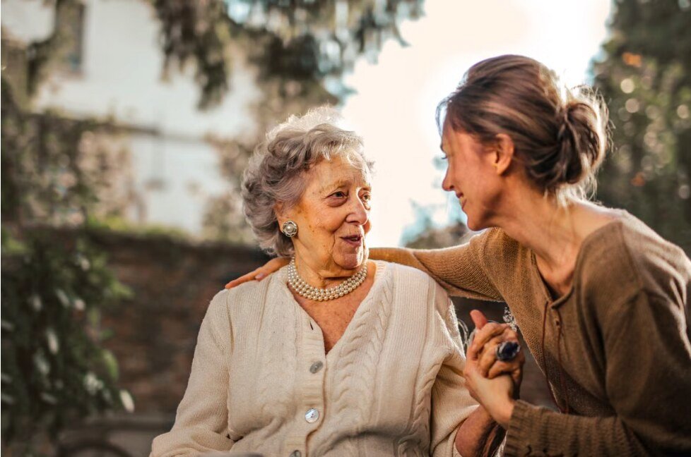Caregiver sharing a warm conversation and companionship with a senior client outdoors