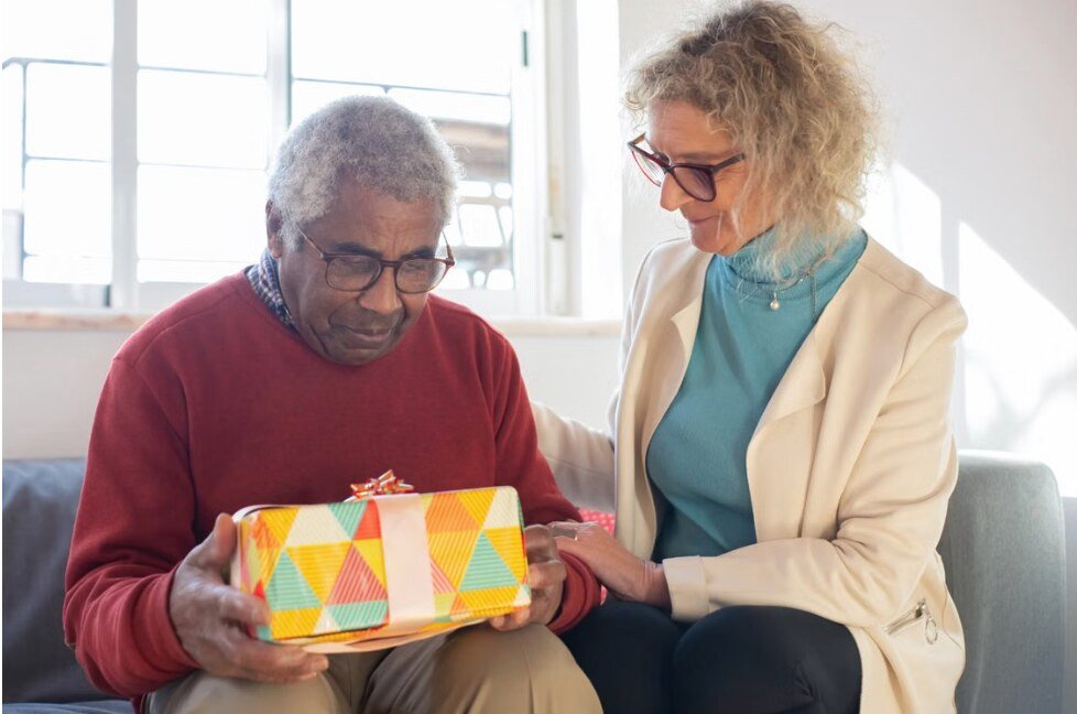 Caregiver presenting a holiday gift to a smiling senior client at home in Pennsylvania